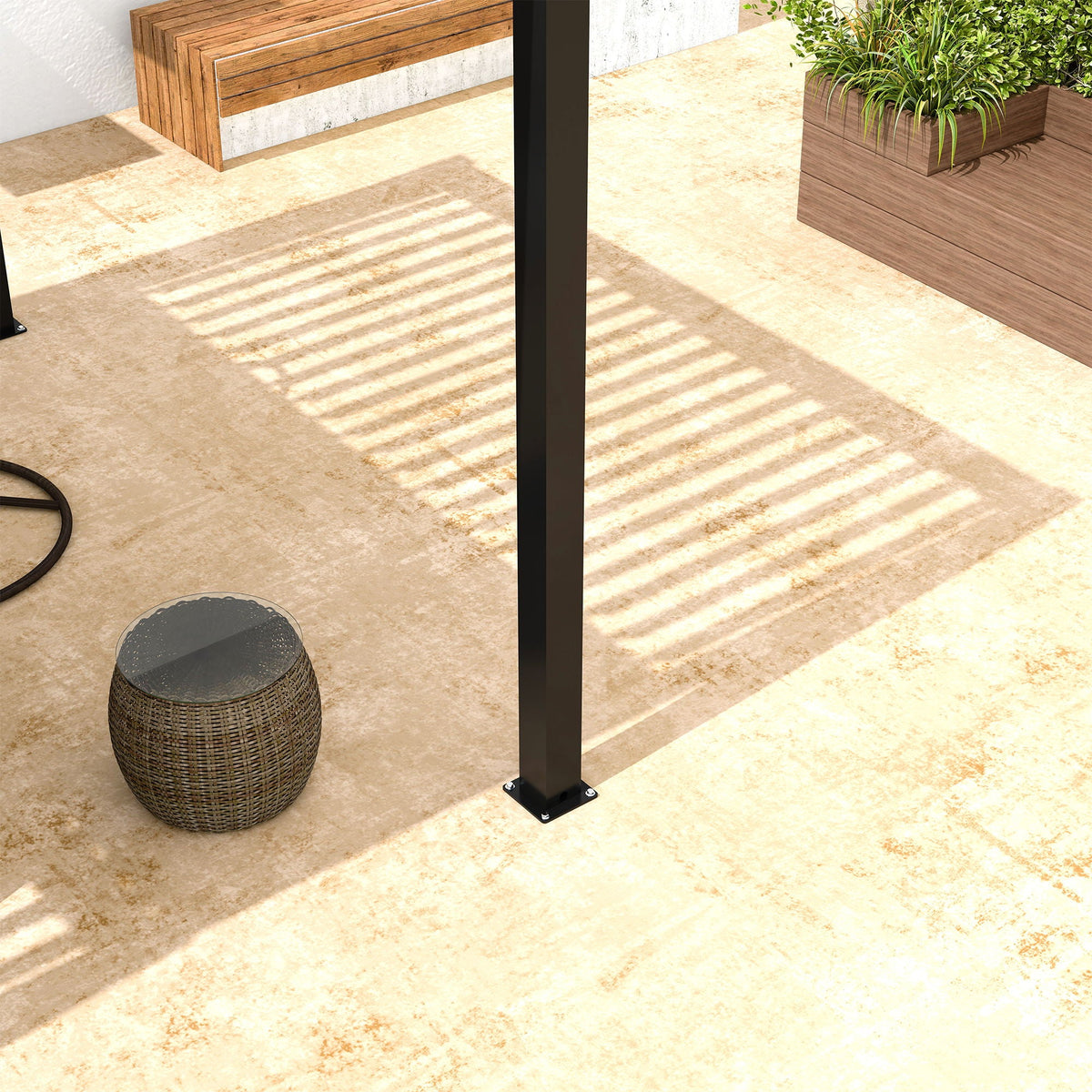 Close-up of black pergola post with base plate anchored on a patio surface.