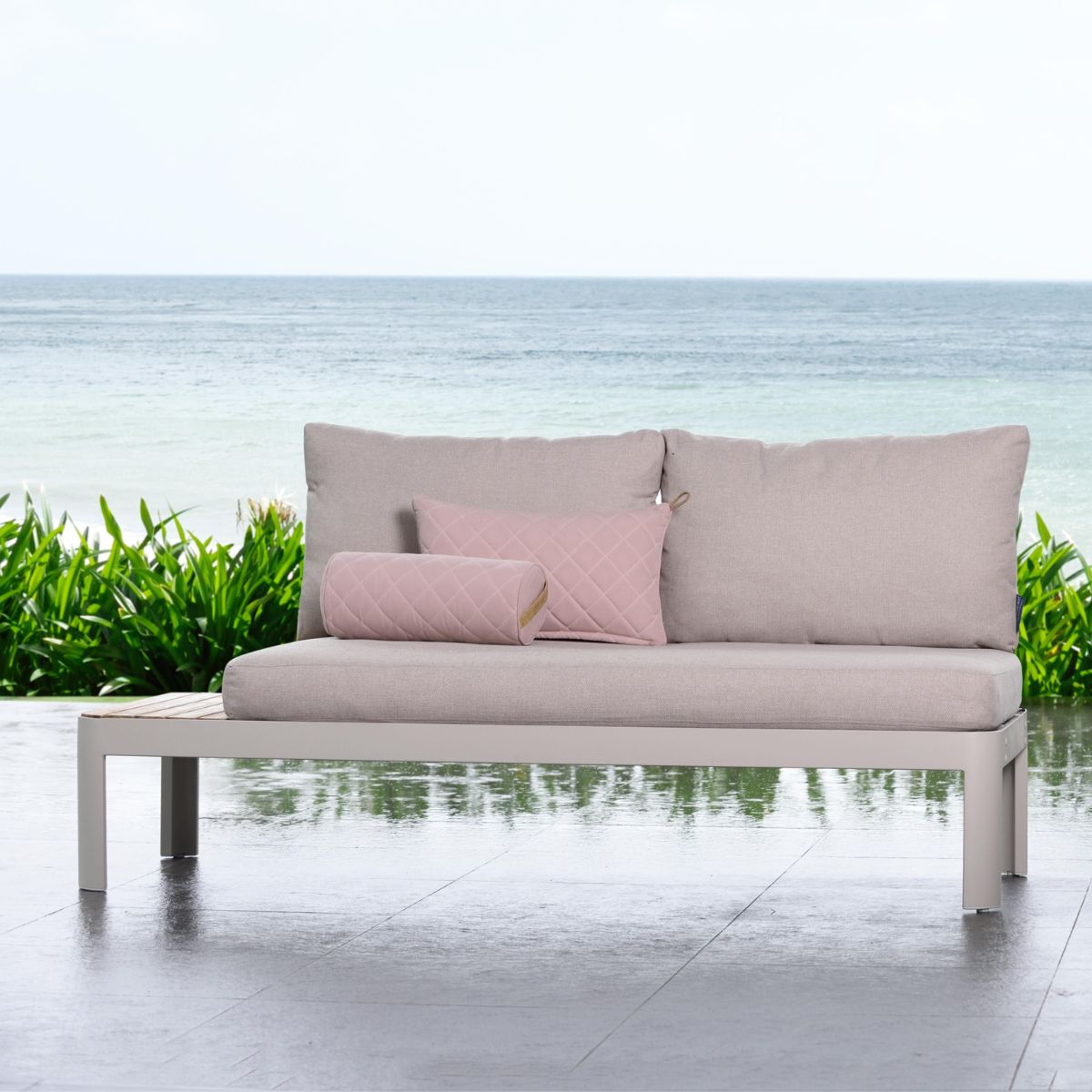 Coral Sand two-seat outdoor sofa with coordinating cushions in a garden setting.