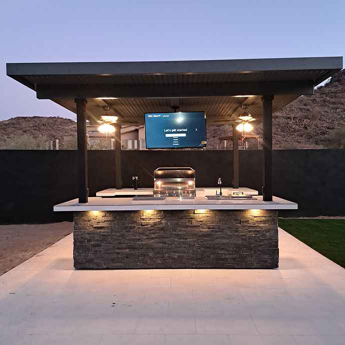 Outdoor kitchen island with a built-in grill and mounted TV.