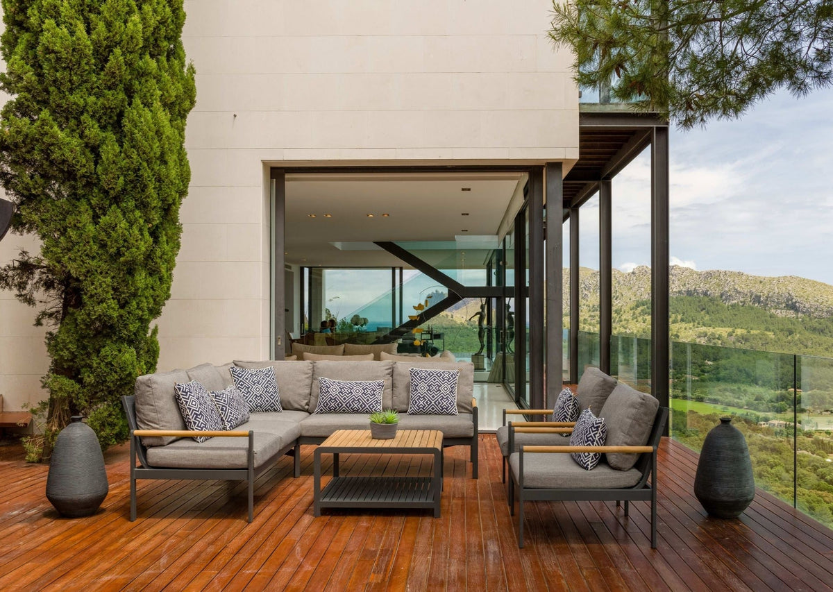Outdoor sectional sofa and square coffee table arranged on a deck.
