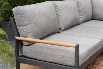 Close view of an outdoor sectional sofa with gray cushions, a dark frame, and a wood-tone armrest.
