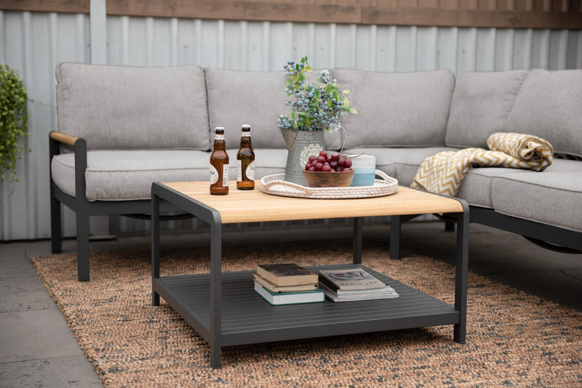 Close view of a square outdoor coffee table with a wood-tone top and lower shelf.
