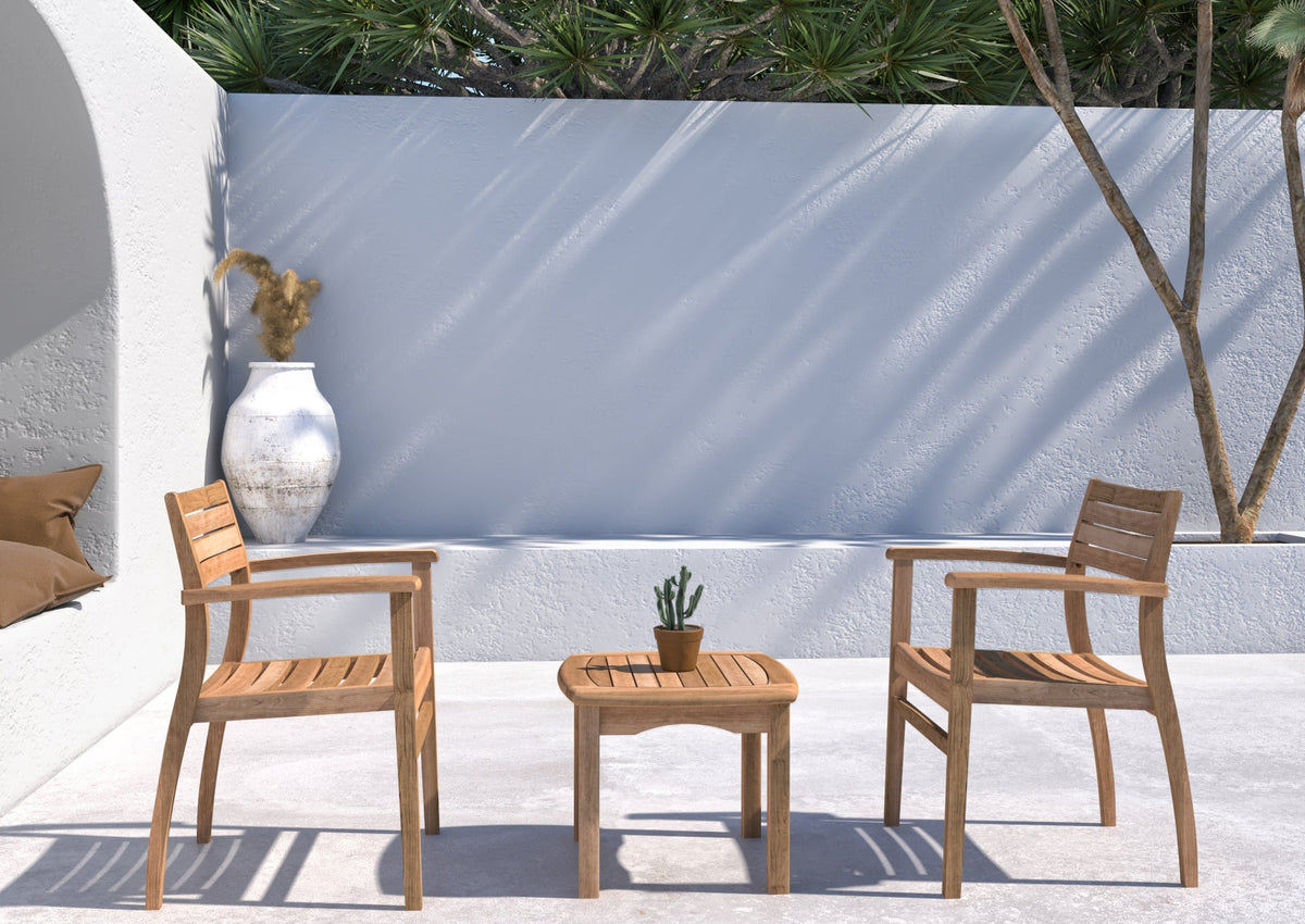 Two teak armchairs and a matching side table arranged on a patio.

