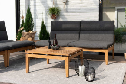 Outdoor seating arrangement with dark cushions and a teak side table.