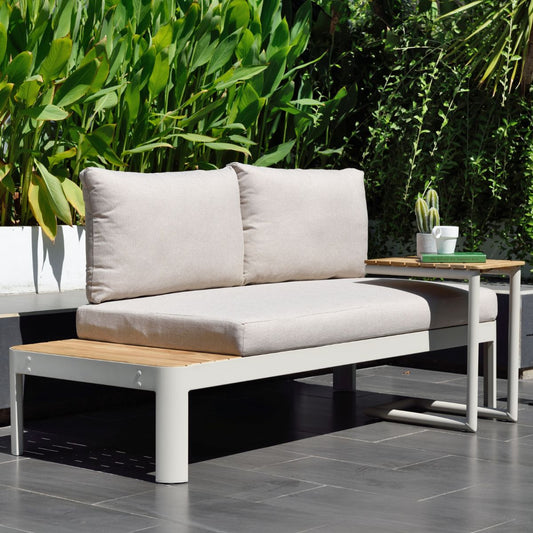Coral Sand outdoor sofa with cushions and a teak side table in a garden setting.