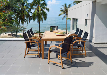Outdoor dining set with an FSC teak table and eight black mesh armchairs beside a tropical ocean view.