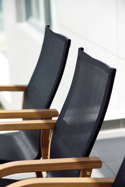 Close-up of two black armchairs with curved armrests and mesh backs.