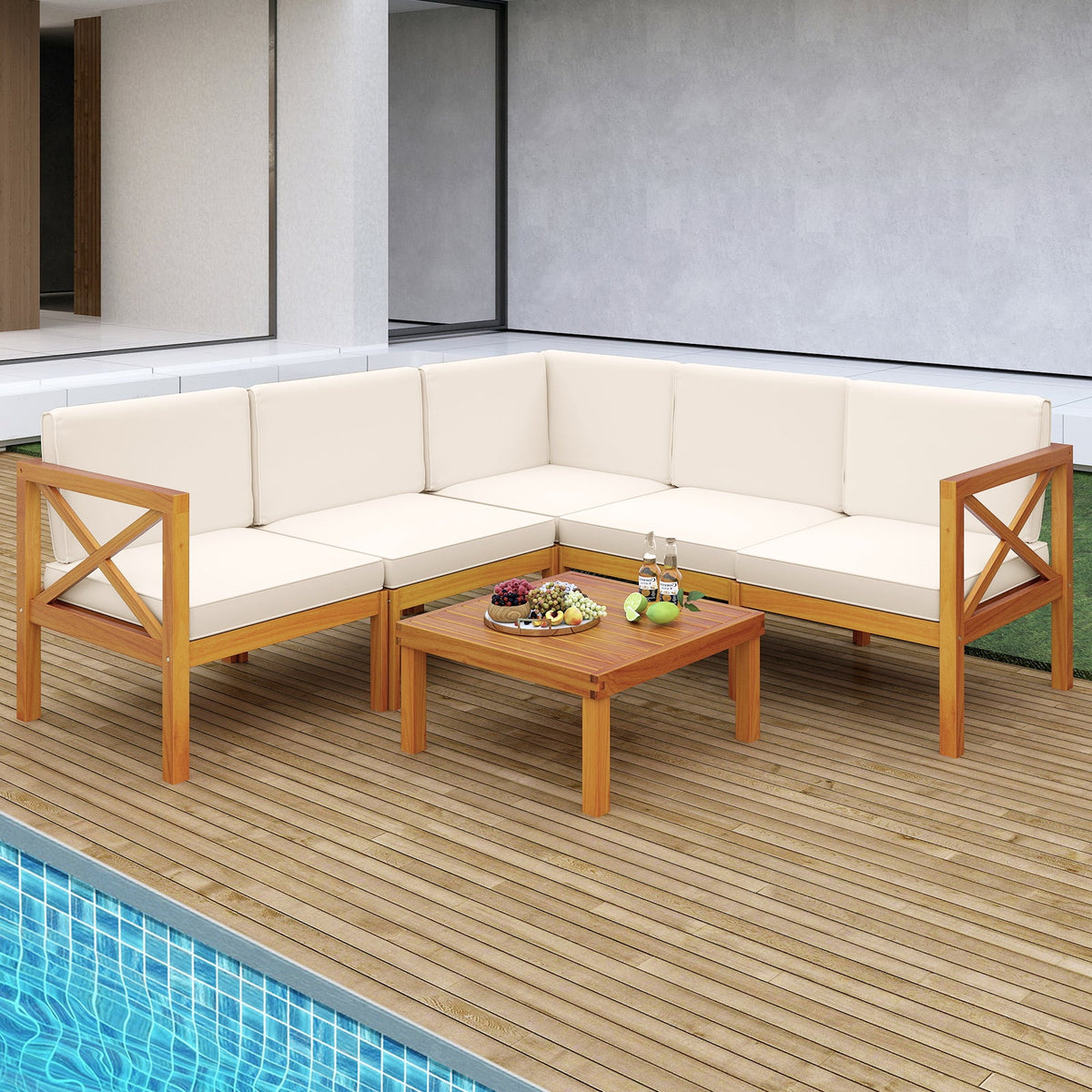 Off-white cushioned acacia wood outdoor sectional with a square coffee table beside a swimming pool.

