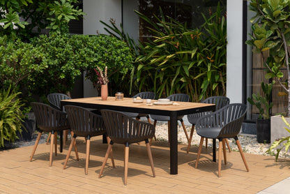 Rectangular FSC-certified teak outdoor dining table with eight black chairs in a garden setting.