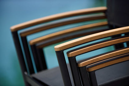 Black stacking armchair with aluminium frame, Weather-net seating, and FSC-certified teak armrest.