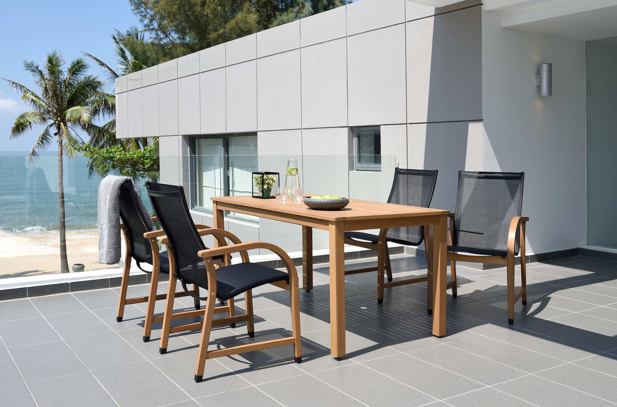 Outdoor dining set with a rectangular wood table and four black armchairs on a patio.
