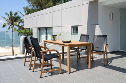 Outdoor dining set with a rectangular wood table and four black armchairs on a patio.
