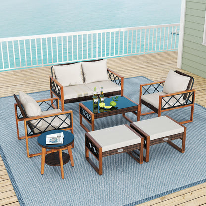 Outdoor conversation set with white cushions on a deck overlooking the water.